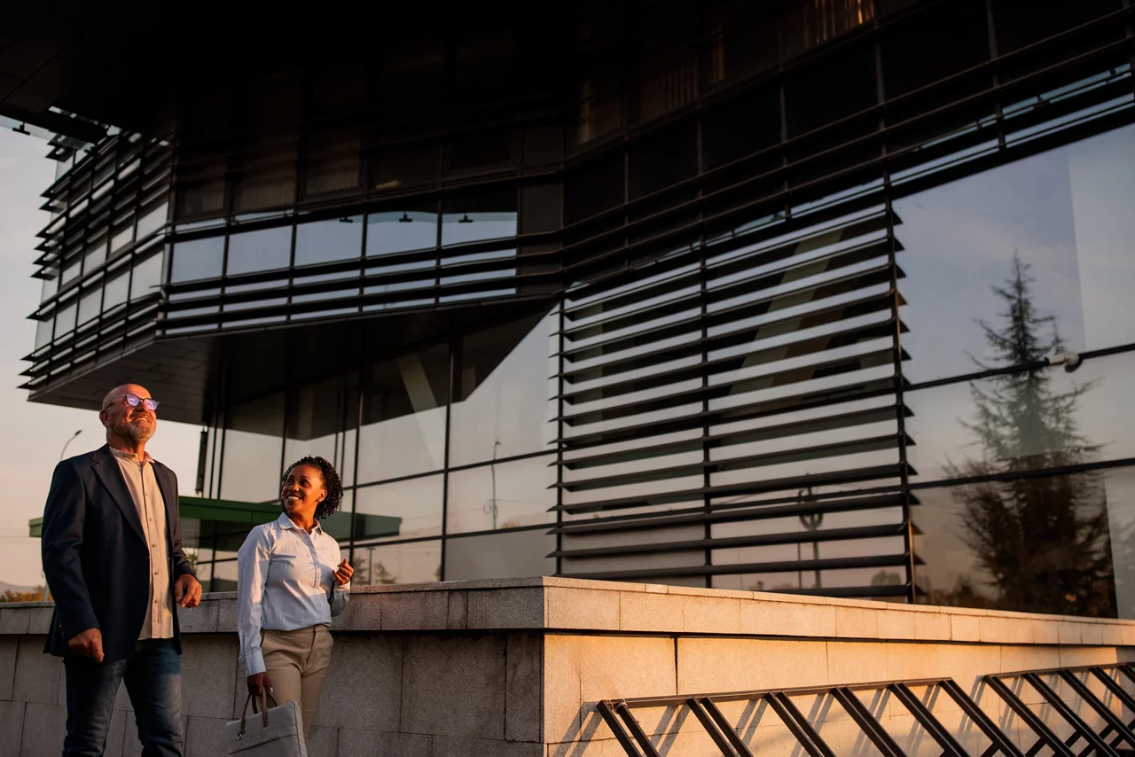 Two people walking outdoors in a business area ,with the office building in the background