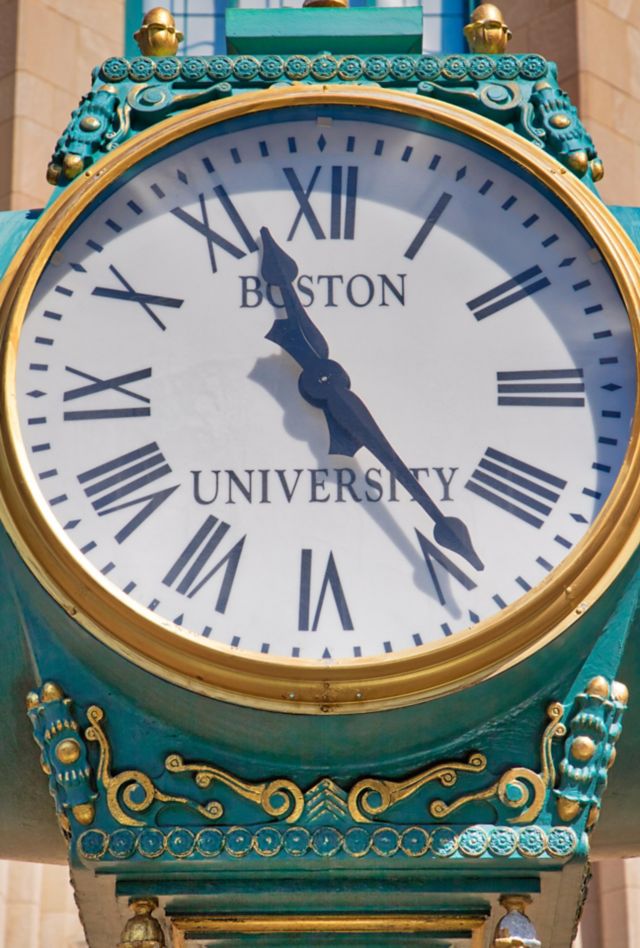 Close up of a large clock outside of a building. The clock face reads "Boston University."